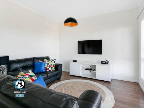 sala de estar con sofá de cuero negro y TV en Ocean & Island Views for Miles – 4BR + 2.5 Baths, en Encounter Bay