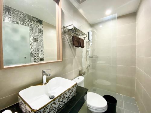 a bathroom with a sink and a toilet and a mirror at WH Chamkarmon Residence in Phnom Penh