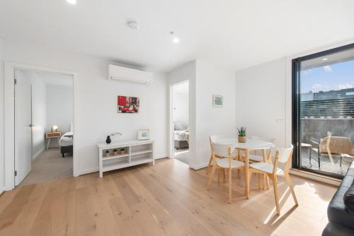 a white living room with a table and a dining room at Queensview168 Apartments Moonee Ponds in Melbourne