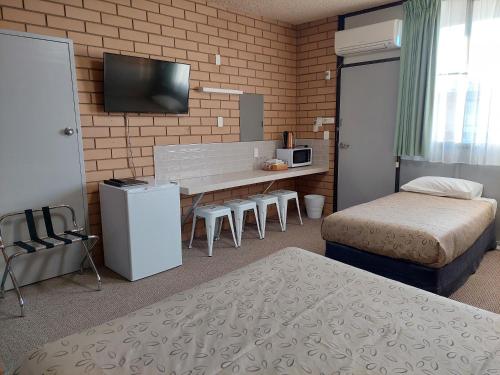 a room with two beds and a desk with a television at Mount Wycheproof Motor Inn in Wycheproof