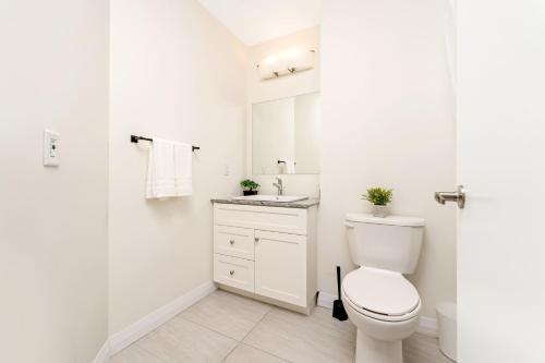 a white bathroom with a toilet and a sink at Upscale 1BR Condo - Balcony - Near Victoria Park in Kitchener