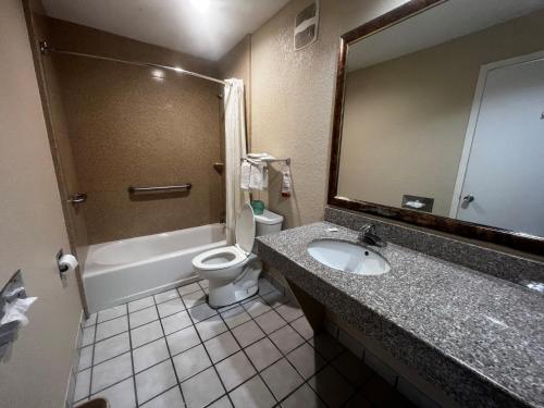 a bathroom with a sink and a toilet and a mirror at Super 8 by Wyndham La Marque TX/Texas City Area in La Marque