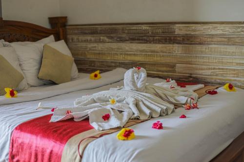 a bed with white towels and flowers on it at Manta Cottages with Sea View in Nusa Penida