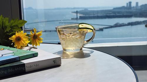 una taza de vidrio sentada en una mesa junto a un libro en Hoa Homestay Hạ Long 2909 en Ha Long