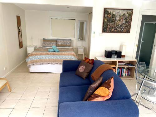 een woonkamer met een blauwe bank en een bed bij Rumah Pantai in Emu Bay