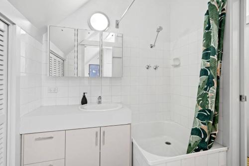 a white bathroom with a sink and a mirror at The Warbling Magpie in Melbourne