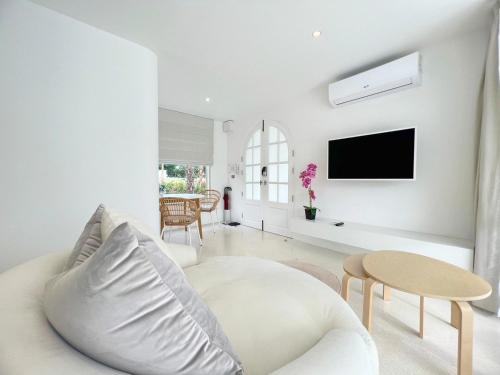 a white living room with a couch and a tv at ทิพย์วาริน รีสอร์ท เขาใหญ่ in Ban Tha Chang