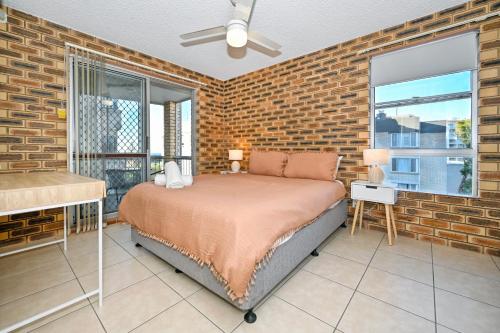 1 dormitorio con cama y pared de ladrillo en Location is Everything - Shops, Beaches, Views ZG3, en Caloundra