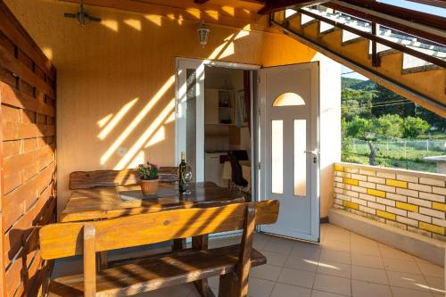 porche con mesa de madera y banco en el patio en Apartment Vesna - 100m from sea en Luka