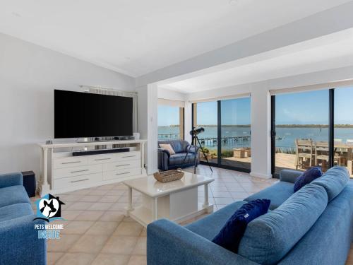 a living room with a blue couch and a flat screen tv at Absolute Water Frontage w/ Jetty + Boat Ramp in Hindmarsh Island