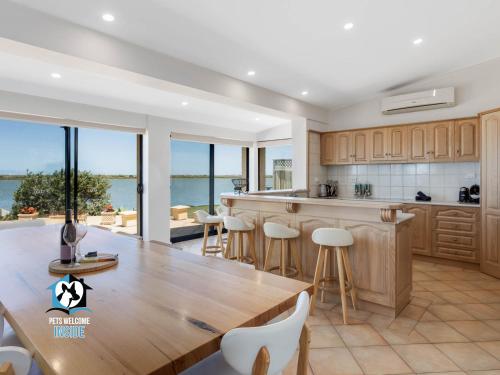 a kitchen with a large wooden table and chairs at Absolute Water Frontage w/ Jetty + Boat Ramp in Hindmarsh Island