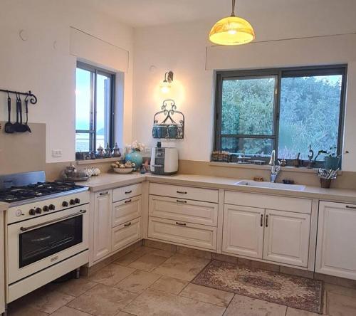 uma cozinha com armários brancos e um forno com placa de fogão em בית לוי em Dishon