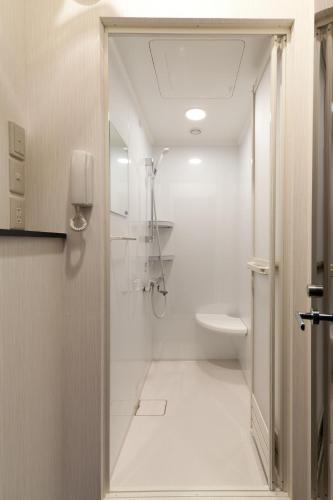 ein weißes Bad mit einer Dusche und einem WC in der Unterkunft Fujiko Building 3F - Vacation STAY 35722v in Yokosuka