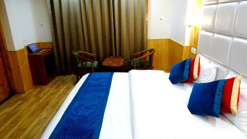 a bedroom with a large bed with blue and red pillows at Humble Holiday Home Kufri S H I M L A with Lawn and Amazing View in Kūfrī