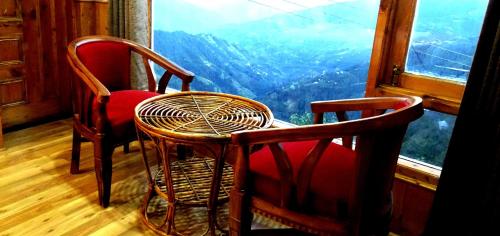 a table and chairs in a room with a window at Humble Holiday Home Kufri S H I M L A with Lawn and Amazing View in Kūfrī