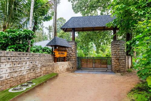 Un mirador con una puerta y un muro de piedra en Shanthi Kunnj Riverside Exotica Chikmagalur, en Chikmagalur