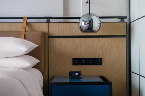 a clock on a side table next to a bed at Four Points by Sheraton Guangzhou, Baiyun in Guangzhou