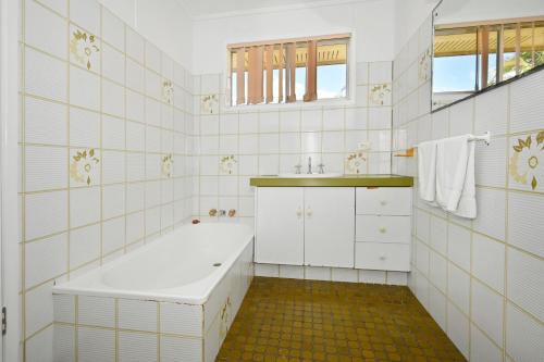 a white bathroom with a tub and a sink at Bungalow on the Beach 4 B/R, 8 Guests, Aircon ZG2 in Buddina