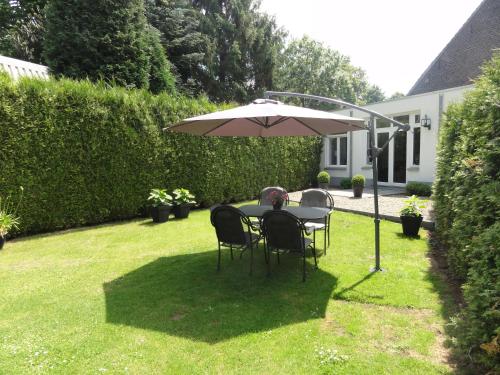 a table and chairs under an umbrella in a yard at B&B Appartementen Engelenhof in Stevensweert