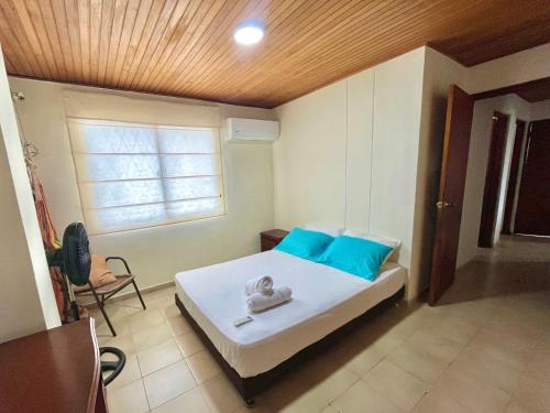 een slaapkamer met een bed met blauwe kussens en een raam bij Excelente apto cerca al mar in Cartagena