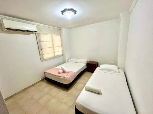een kleine kamer met 2 bedden en een raam bij Excelente apto cerca al mar in Cartagena