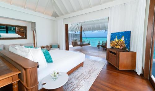 a bedroom with a white bed and a piano at Anantara Kihavah Maldives Villas in Baa Atoll