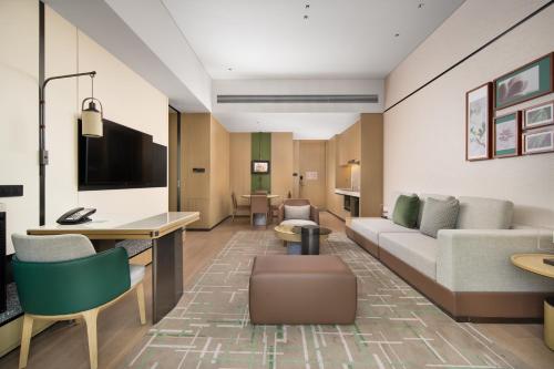 a hotel room with a couch and a table and chairs at Element Guangzhou Baiyun in Guangzhou
