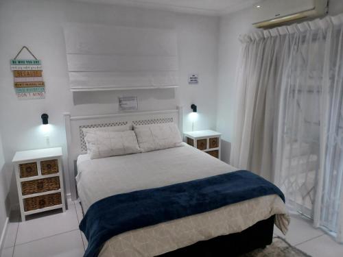 une chambre blanche avec un lit et deux tables de nuit dans l'établissement Close to the sea - Ground floor En-suite room with kitchenette & own entrance, à Durban