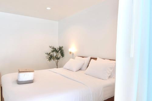 a white bedroom with a white bed with a laptop on it at Beachfront Deluxe pool access room one-minute walk to Wonnapha beach in Bangsaen