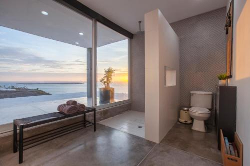 a bathroom with a toilet and a view of the ocean at Villa Wellmina - Stunning Sunsets & Relaxing Poolside Vibes! in La Paz