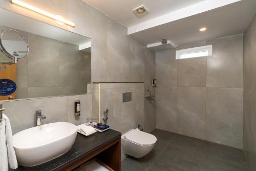 a bathroom with a sink and a toilet and a mirror at Cozzet Victoria Hotel in Bhubaneshwar