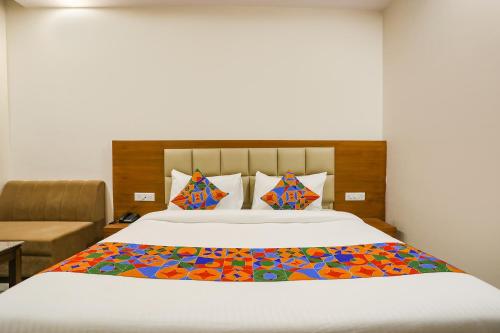 een slaapkamer met een groot bed en een kleurrijke deken bij FabHotel Aman Sara in Lucknow