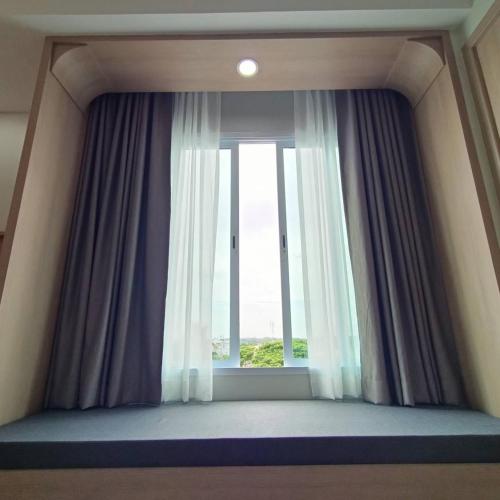 a room with a large window with curtains at Mayflower Grande Suite Hotel in Phitsanulok