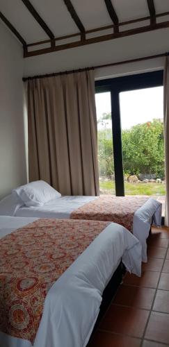 a bedroom with two beds and a large window at El Garabandal in Villa de Leyva