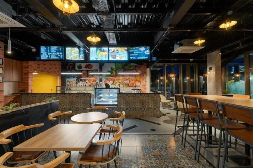 a restaurant with tables and chairs and televisions at Cozzet Victoria Hotel in Bhubaneshwar