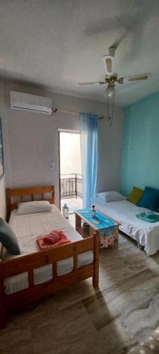 a bedroom with two beds and a table and a window at Angel's Place by the Sea in Diakopto