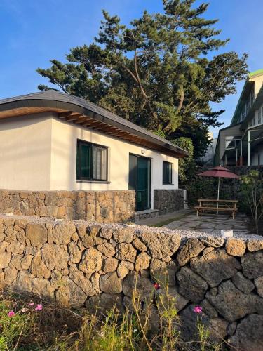 a stone wall in front of a house at Joohane Jejudo House in Jeju