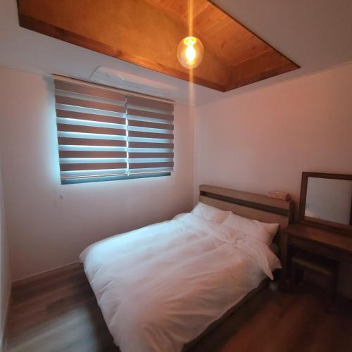 a bedroom with a white bed and a window at Joohane Jejudo House in Jeju