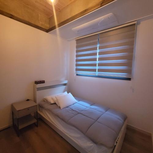 a small bedroom with a bed and a window at Joohane Jejudo House in Jeju
