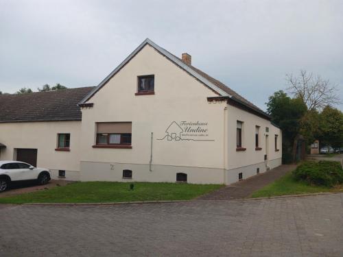 a white building with a sign on the side of it at Ferienhaus Undine mit E-Auto-Ladestation in Oranienbaum-Wörlitz