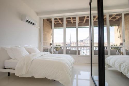 - une chambre blanche avec 2 lits et une grande fenêtre dans l'établissement LUXE SUR LE PORT, à Marseille