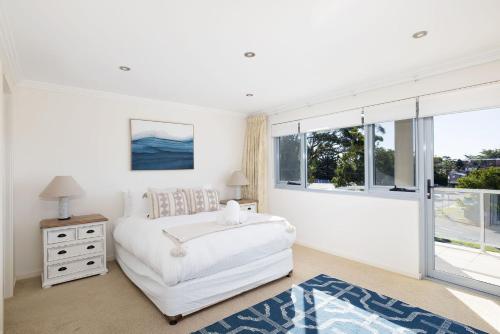 a white bedroom with a bed and a window at Nelson Bay Apartment with views over the Marina in Nelson Bay
