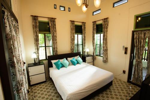 um quarto com uma grande cama branca com almofadas azuis em วิลล่าขุนวิเชียรพานิช em Phetchaburi