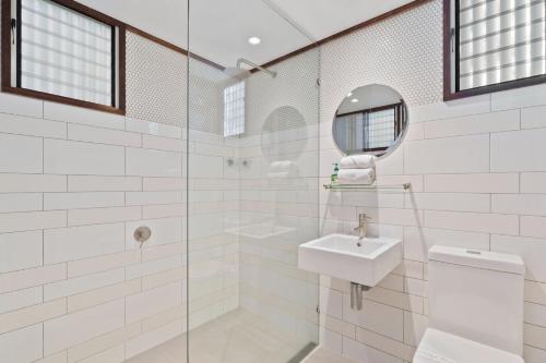 a white bathroom with a sink and a mirror at Moonshine Beach Shack by Discover Stradbroke in Point Lookout