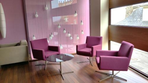 a waiting room with purple chairs and a table at Isla Nova Hotel in Foz