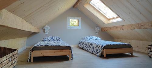 a attic room with two beds and a window at La petite châtaigne in Valdeblore