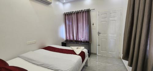 a small bedroom with a bed and a window at Bliss Beach Villa in Alleppey