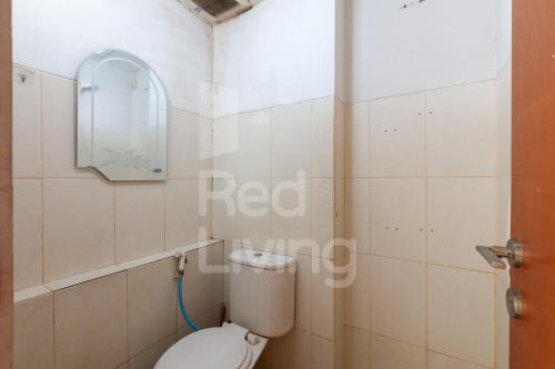 a bathroom with a toilet and a mirror at RedLiving Apartemen Green Lake View Ciputat - Aurora Rooms in Pondokcabe Hilir