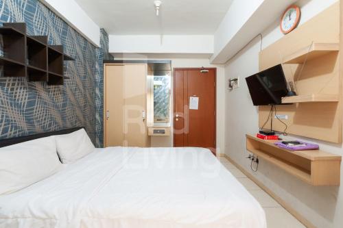 a bedroom with a white bed and a tv at RedLiving Apartemen Green Lake View Ciputat - Aurora Rooms in Pondokcabe Hilir