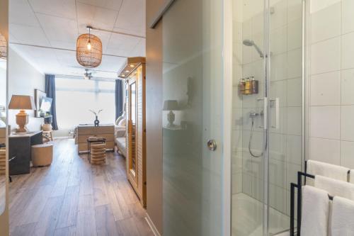 a bathroom with a glass shower and a living room at Aqua Hotel in Konstanz